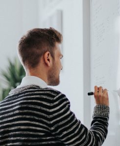 photographie d'un homme d'affaires qui écrit sur un tableau blanc au marqueur noir