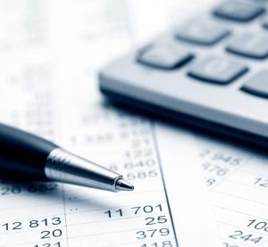 photographie d'un stylo posé sur des feuilles de comptabilité et une calculatrice